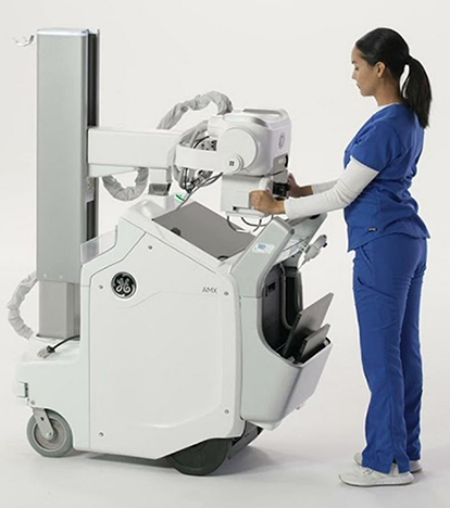 Female radiological technician standing next to a GE AMX X-ray machine