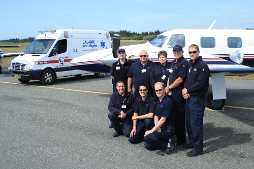 Picture of Curry Ambulance Services Staff standing outside in front of a small jet plane and an ambulance.