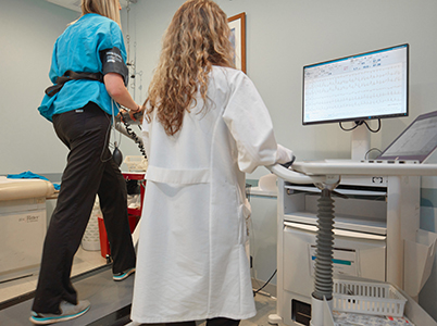 patient on treadmill receiving cardiac stress test, computer monitored by radiologic technician